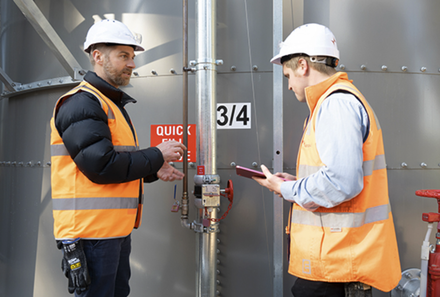 Two team members discussing building services equipment with a tablet on site