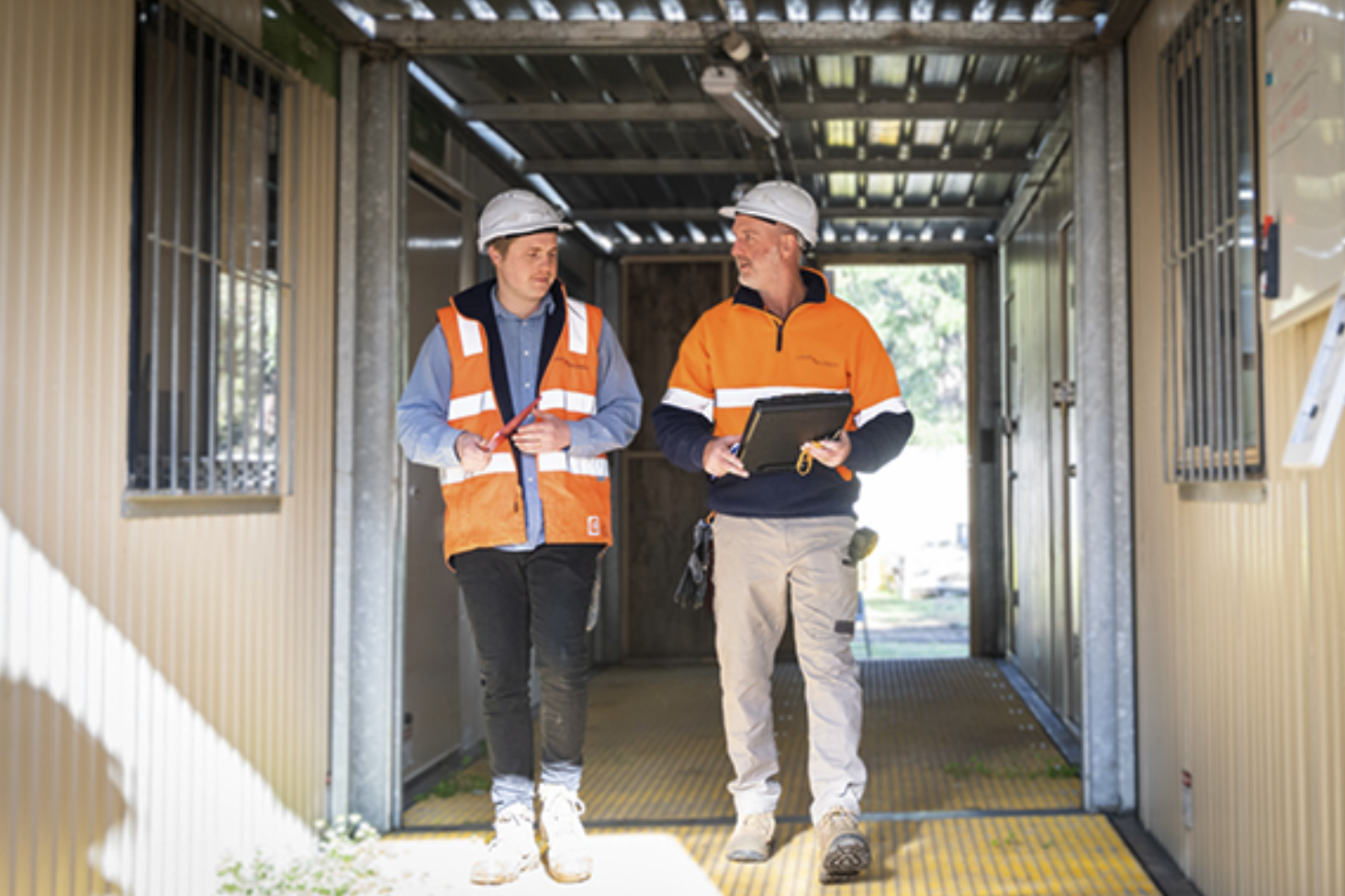 Two team members in hard hats discussing their work during a site walk