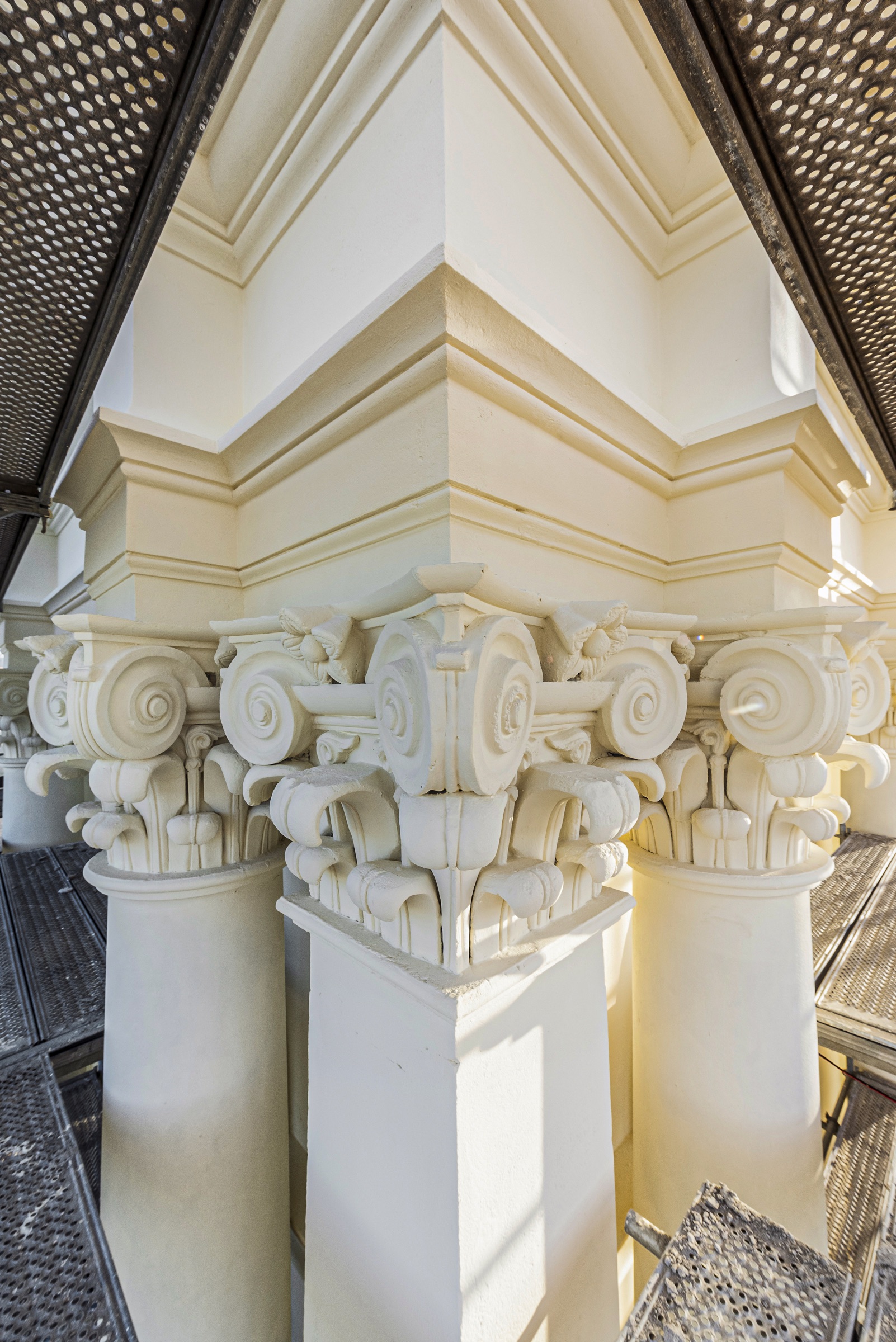 Decorative column capital and facade detail viewed within the scaffold